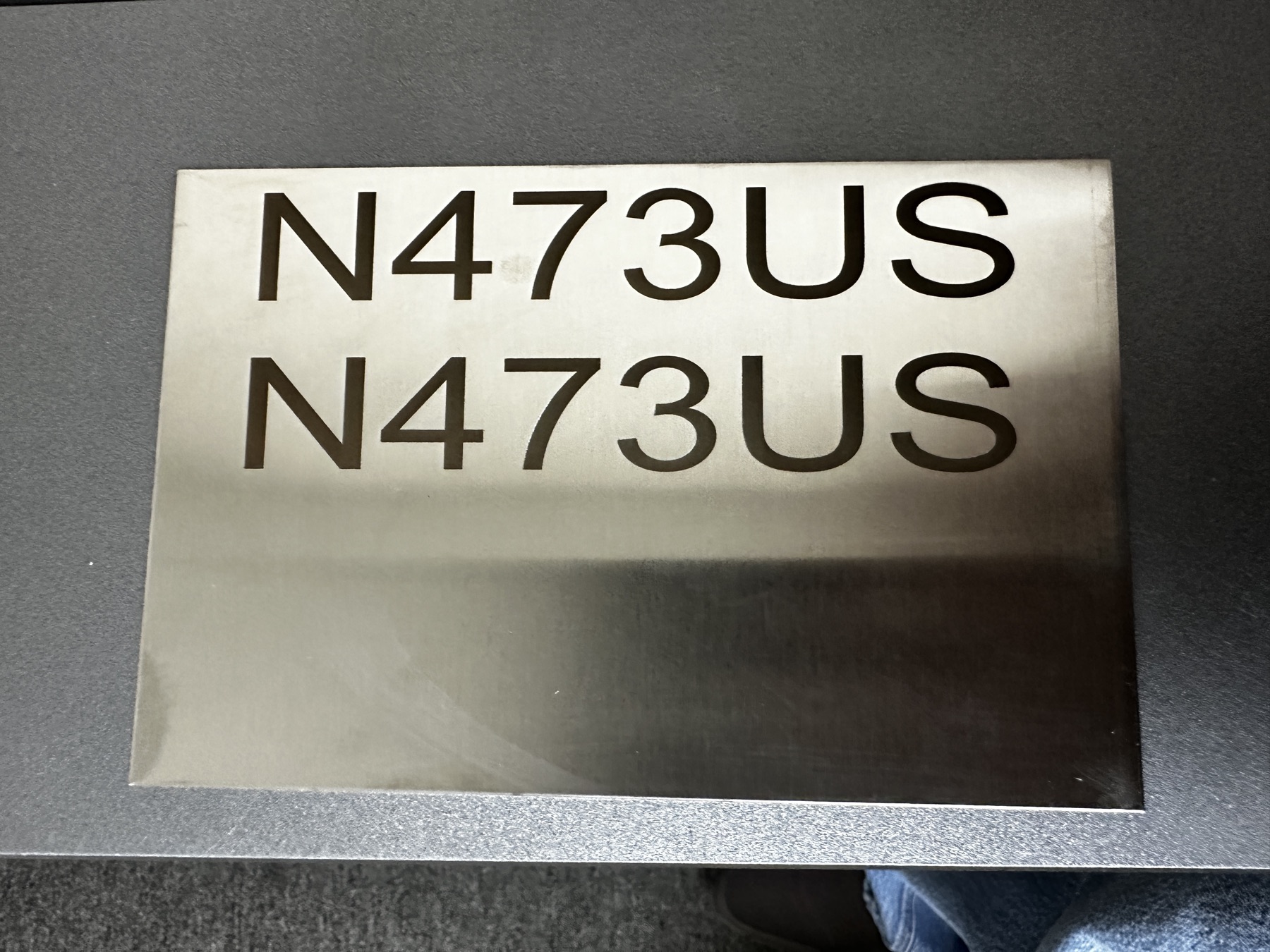 Sample stainless plate showing the same N473US text marked at two different depth settings to demonstrate contrast options