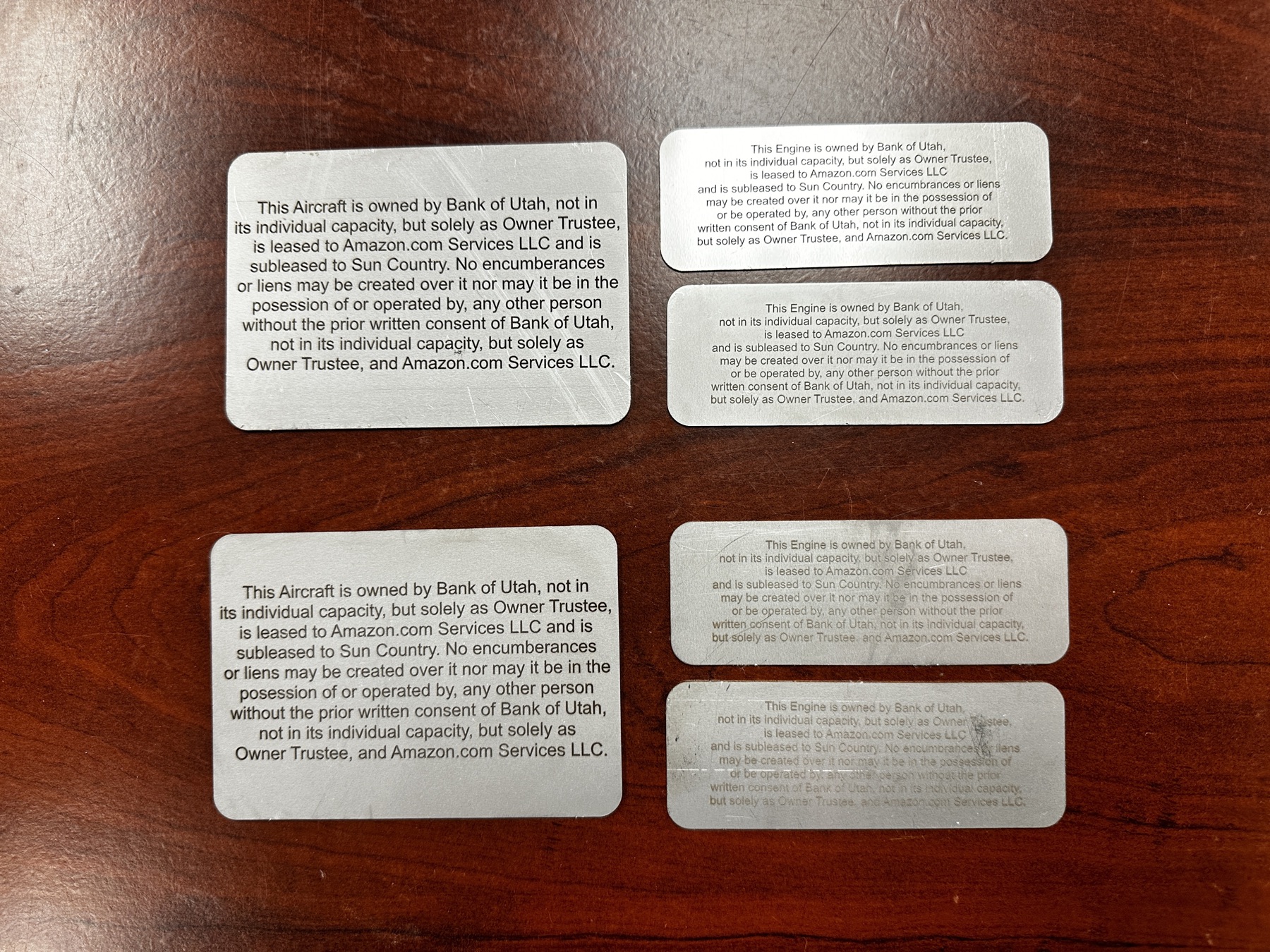 Six ownership plates arranged in two columns: two large aircraft ownership plates on the left and four smaller engine ownership plates on the right, all naming Bank of Utah as owner trustee, Amazon.com Services LLC as lessee, and Sun Country as sublessee